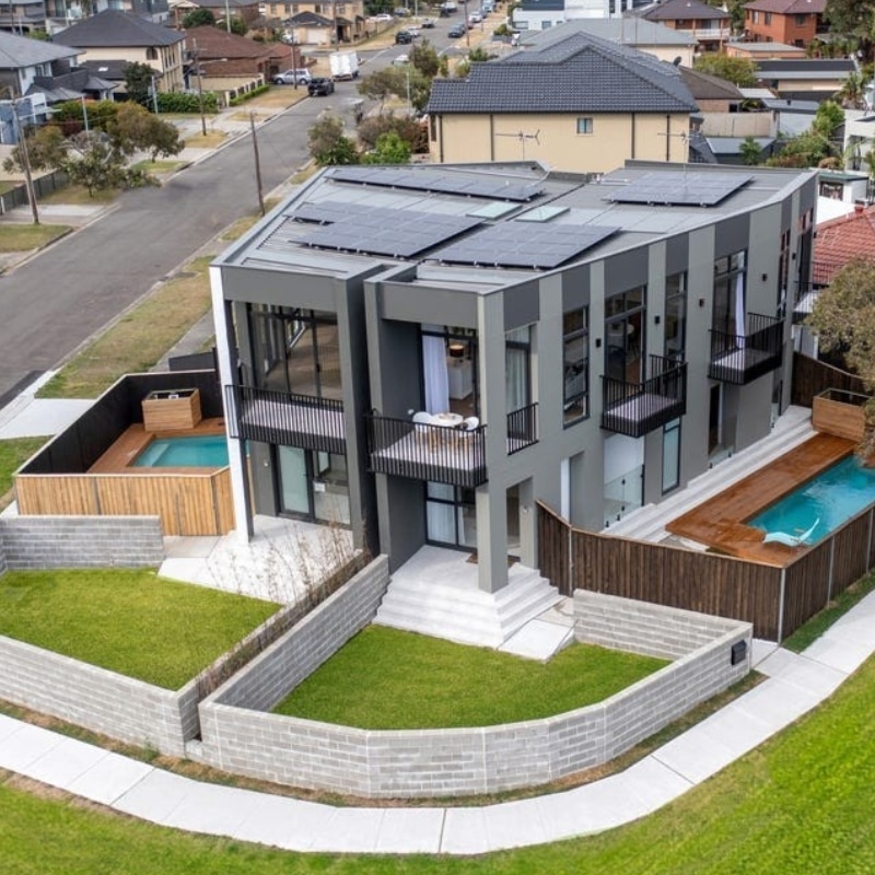 Modern two-storey duplex at 55 Eyre Street, Chifley, 2036, featuring solar panels, landscaped lawns, outdoor pools, and spa areas.