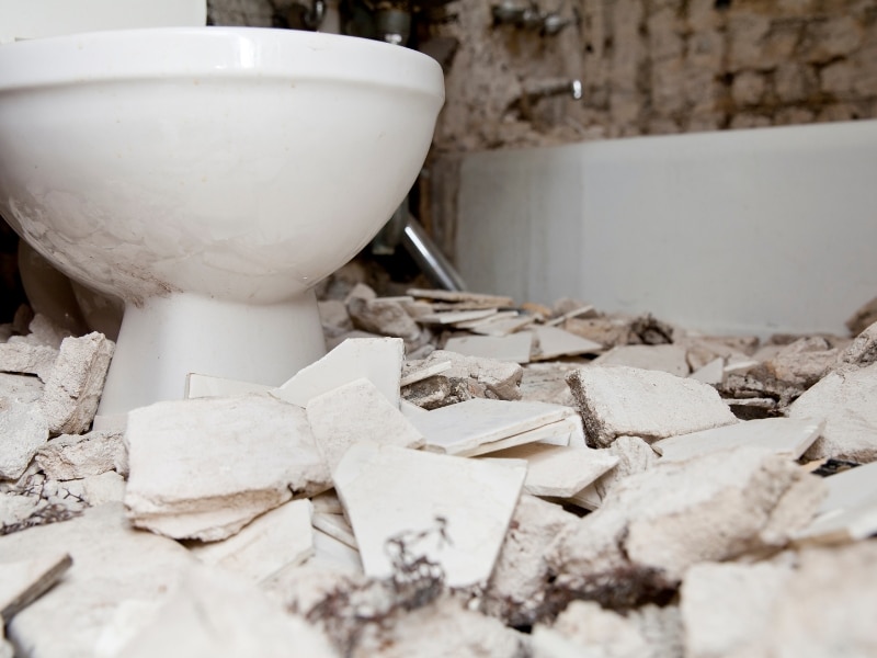 Demolition debris during renovating a bathroom with broken tiles and exposed plumbing