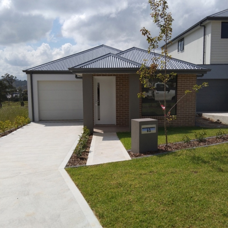Two-storey house in Leppington Project Homes featuring brown brickwork, grey and white painted finishes, and a spacious landscaped front yard.