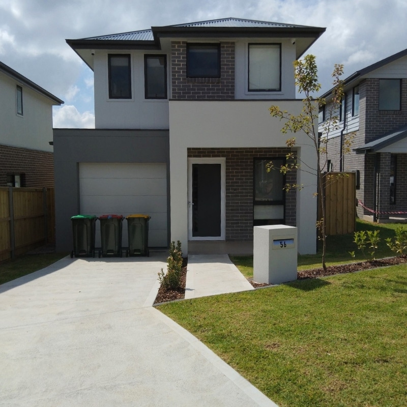 Modern two-storey home in Leppington Project Homes featuring brown brickwork, grey and white painted exterior, and expansive landscaped surroundings.