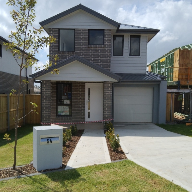 A modern two-story house in Leppington with brick exterior, a front porch, and a garage, surrounded by freshly landscaped lawn and a new construction site nearby.