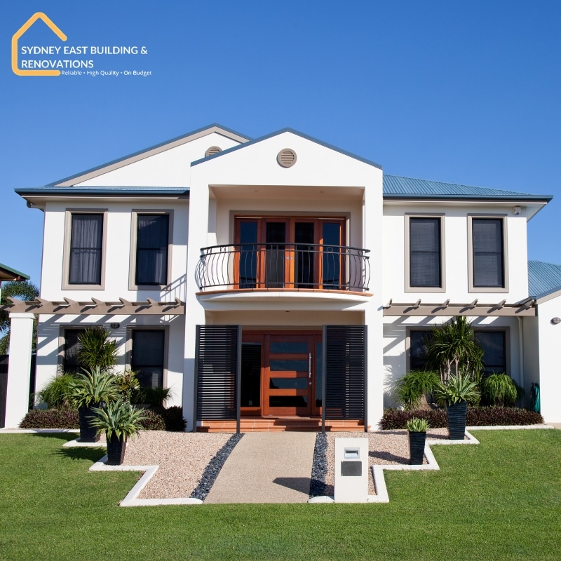 Modern two-storey duplex with balcony, timber door, landscaped frontage, and Sydney East Building & Renovations signage — showcasing Eastern Suburbs Duplex Specialists.