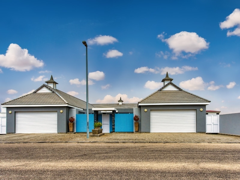 Symmetrical duplex design with dual garages and blue facade.