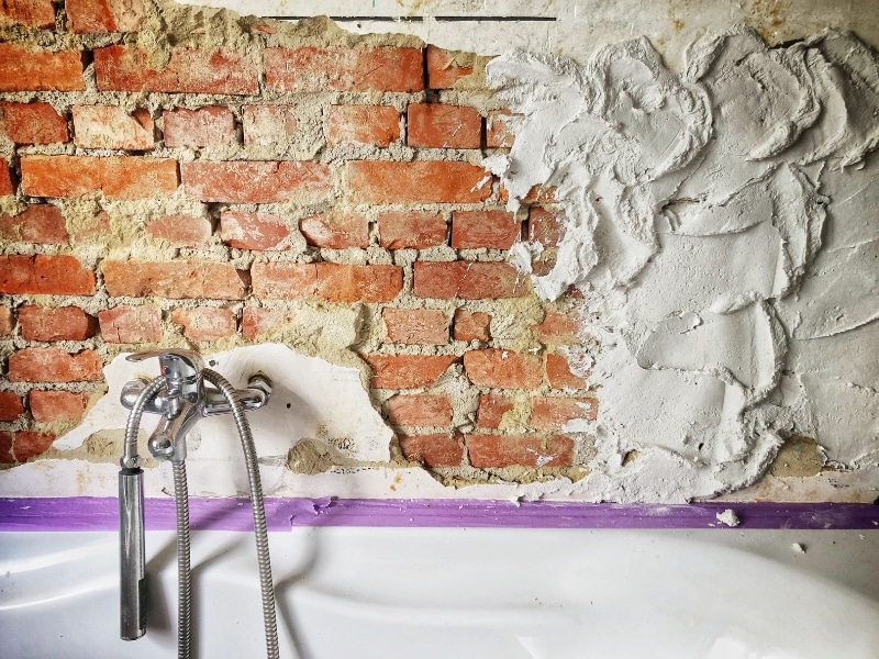 Old bathroom renovation showing exposed brick wall and plaster repair.