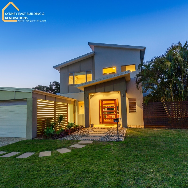 Contemporary two-story house with modern landscaping in Bronte , featuring lush greenery, a dark wooden fence, and a welcoming entrance.